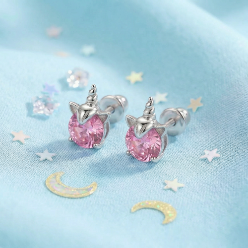 Unicorn-shaped earrings with pink gemstones on a blue background with stars and moons.